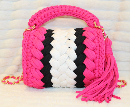 Back of the bag in natural lighting: Hot Pink, White, and Black Crochet woven handbag with Hot Pink tassel sitting on a white textured background