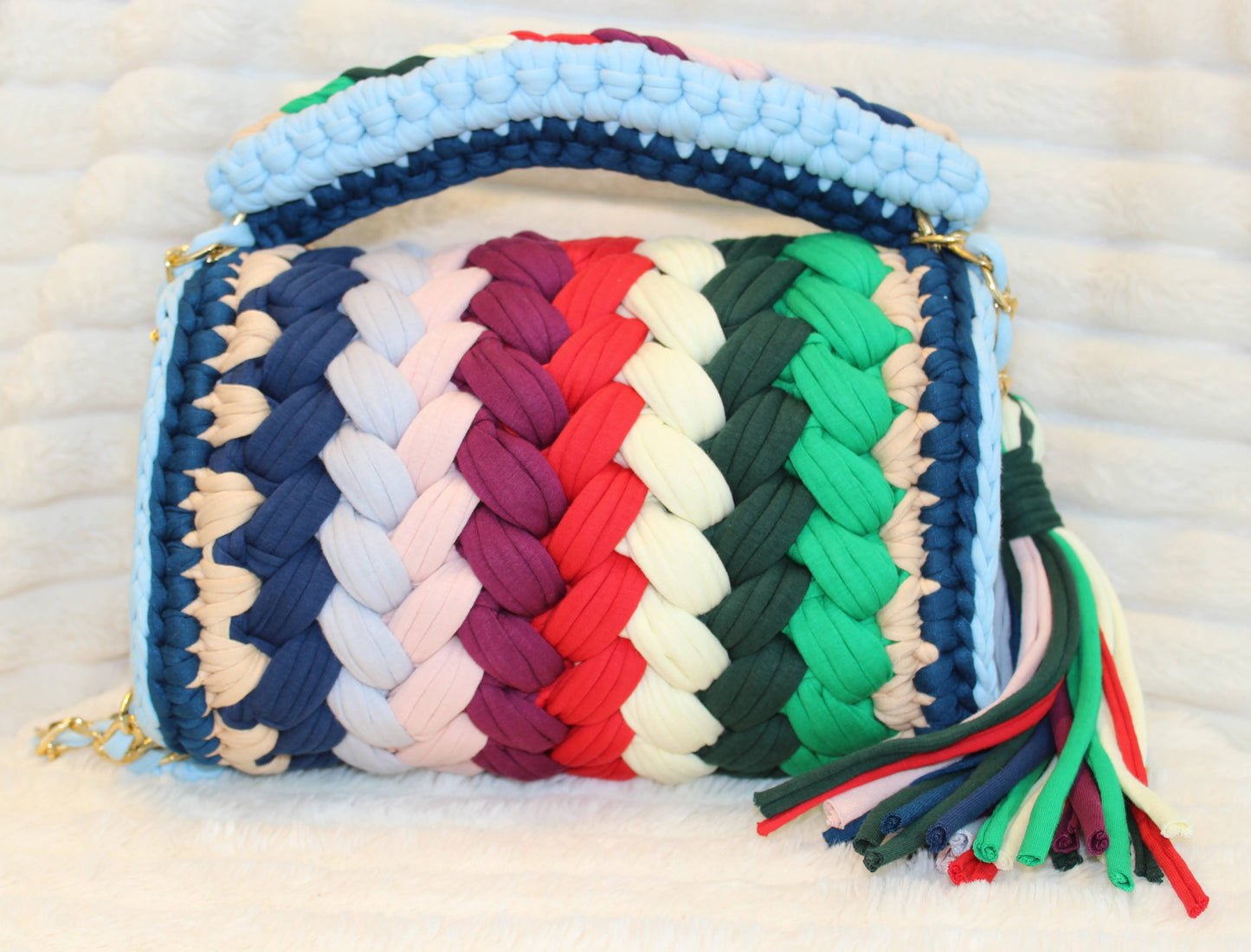 Back view of bag: Colorful handbag in Crochet woven design with tassel on a White textured surface. Bag colors include: Tan, Blue, Green, Forest Green, Red, Burgundy, Soft Yellow, Nude, Light Blue, and Dark Blue.