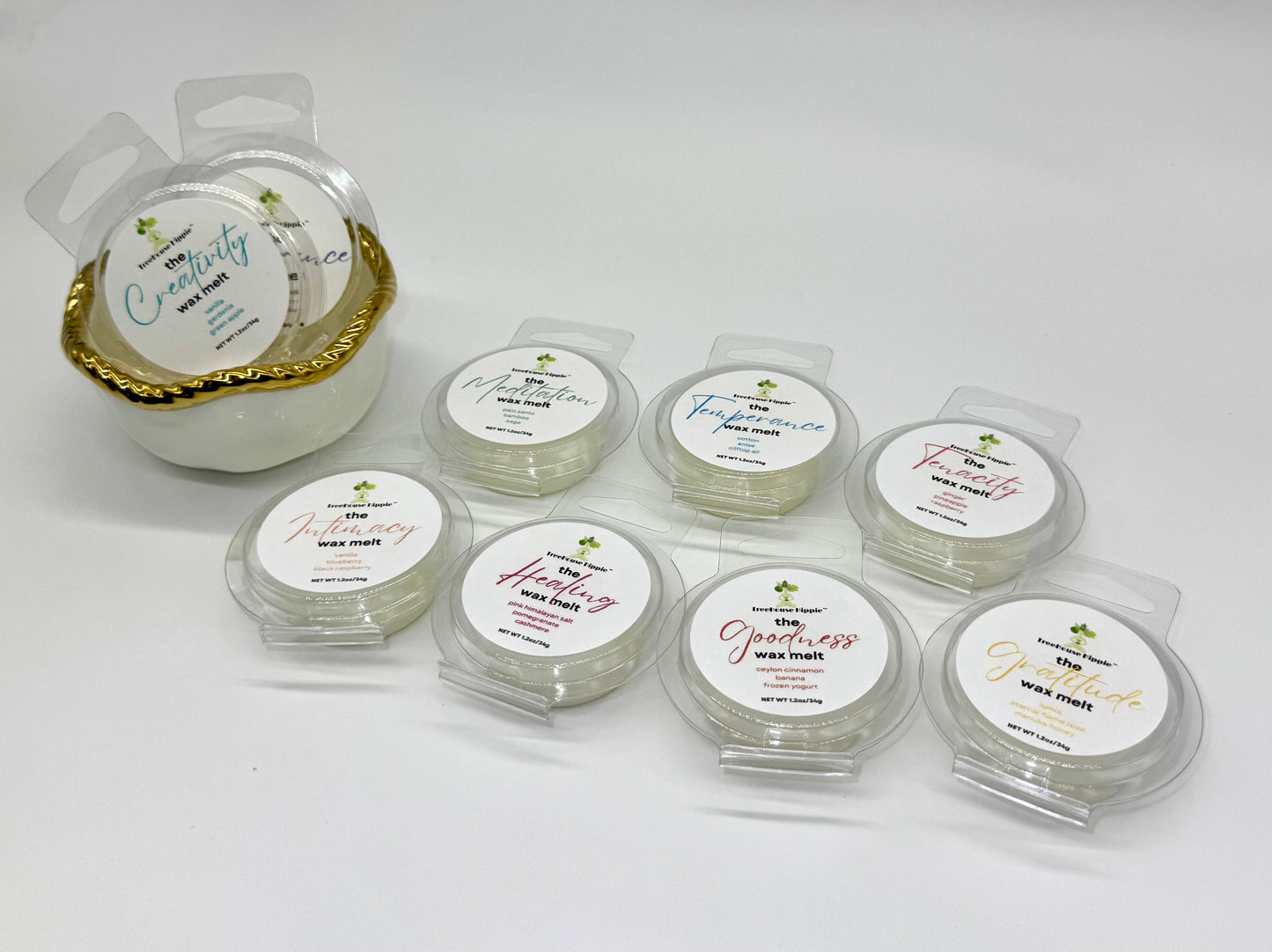 Collection of 10 wax melts in clear containers with white labels on a white background; white bowl with gold trim on the left side.