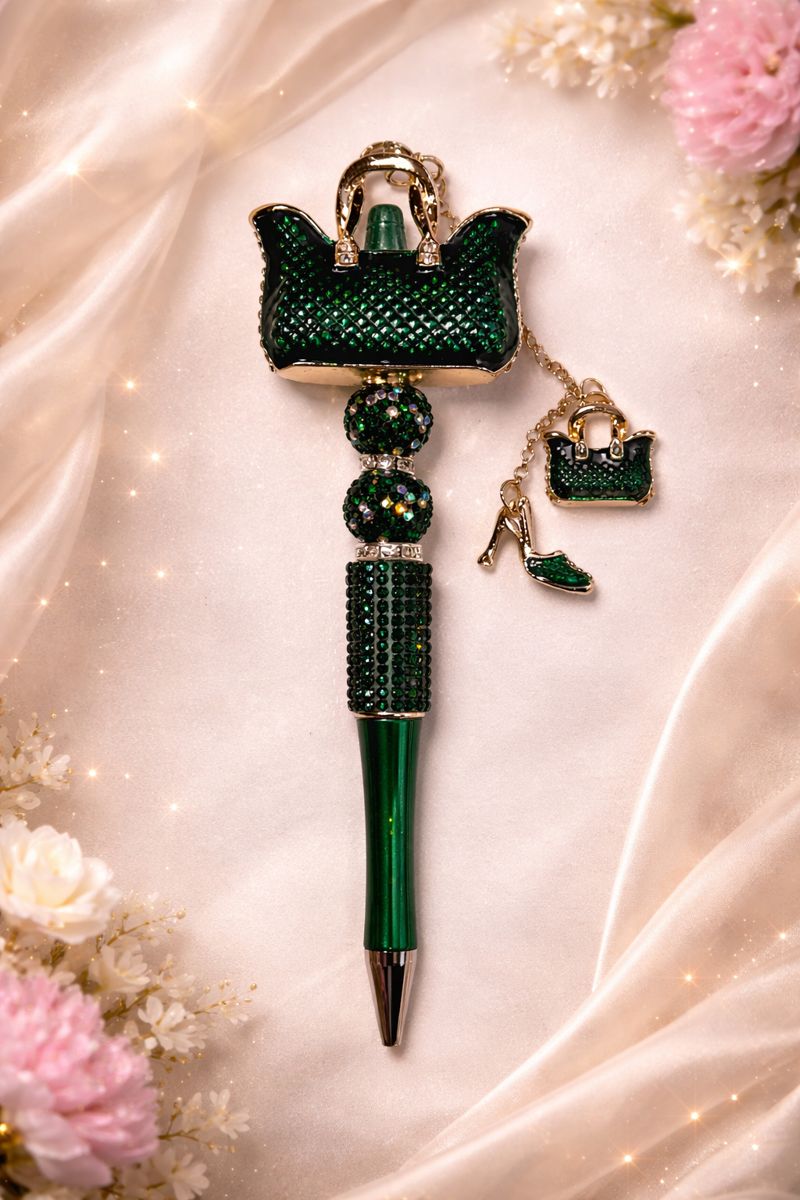 Green bling pen with purse charm decorative top on a soft fabric background with flowers