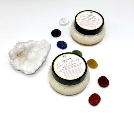 Two of TreeHouse Hippie's ‘Sunlit Honey’ scrubs sitting on a white background with chakra stones and a white quartz crystal.
