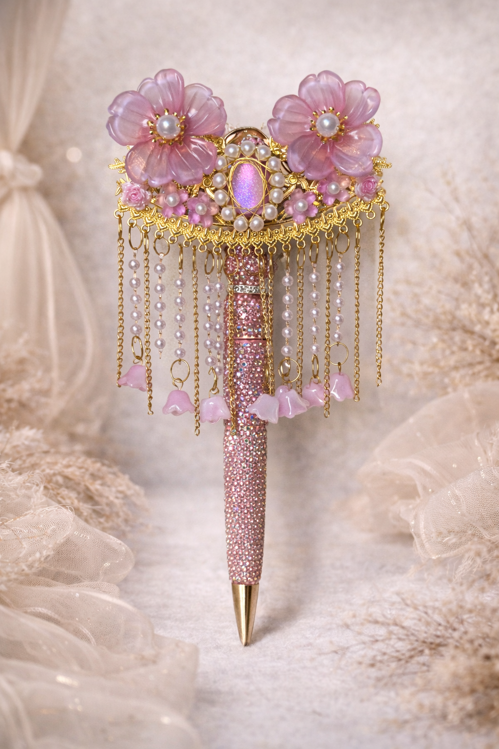 Decorative double-sided pink and gold  bling pen with two large flowers, smaller flower accents, and shiny beaded embellishments on a lace and linen background. 