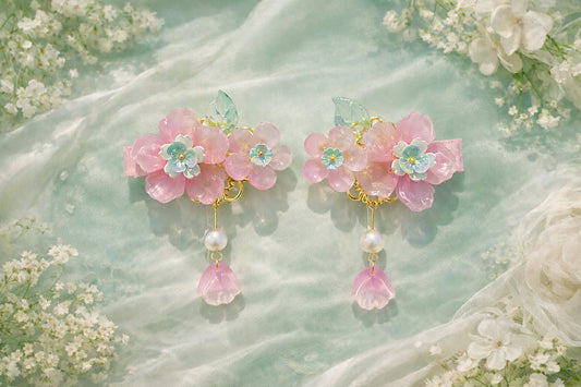 Pink flower hair clips with pearl beaded accent on a soft mint-green background with white floral decor. 