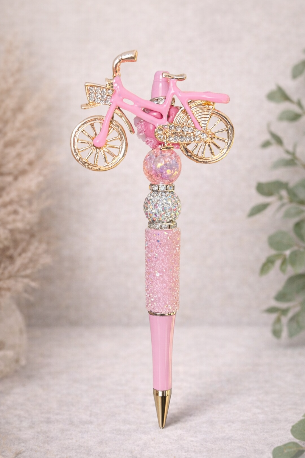 Pink bicycle-charm bling pen on a neutral background