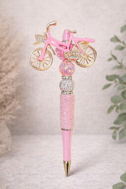 Pink bicycle-charm bling pen on a neutral background