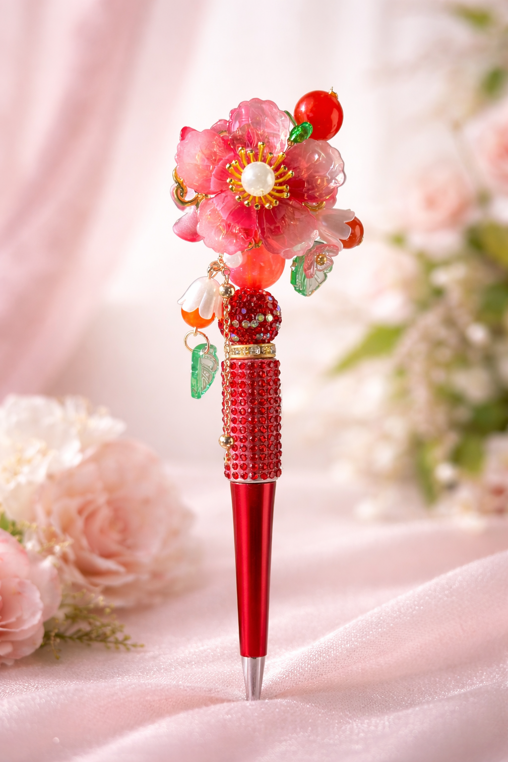Red decorative pen with cherry blossom top on a soft pink background