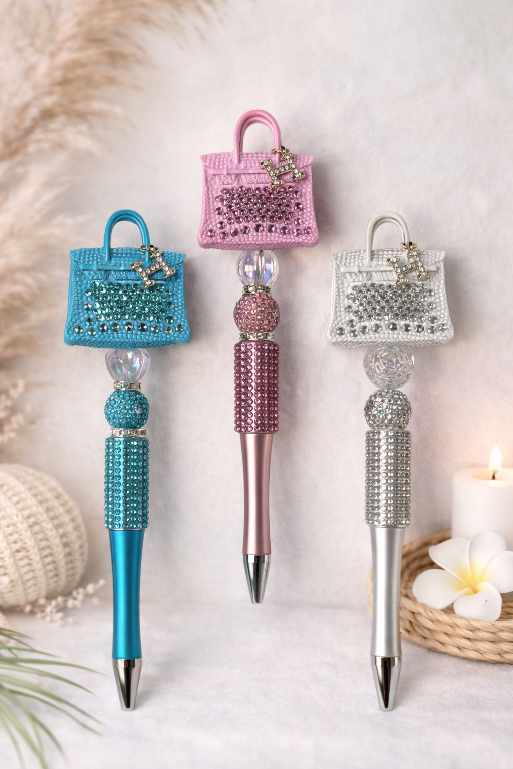 Three decorative pens (blue, pink, and white) shaped like handbags on a light background