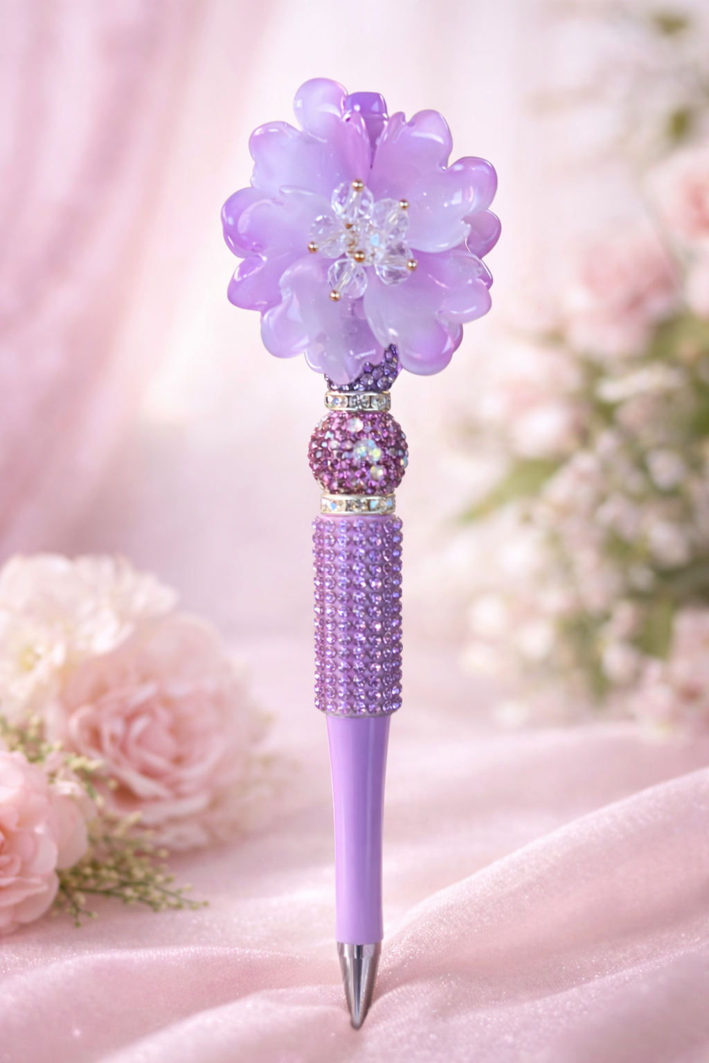 Decorative purple bling pen with a flower top on a soft pink background