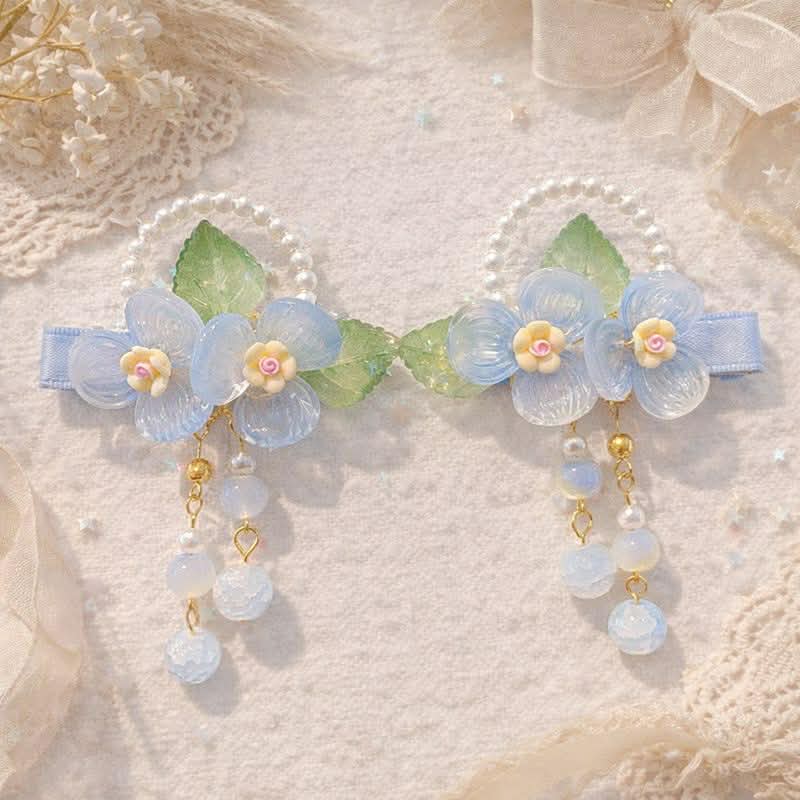 Blue flower hair clips with pearl bead bow and green leaves on a lace and paper textured white background