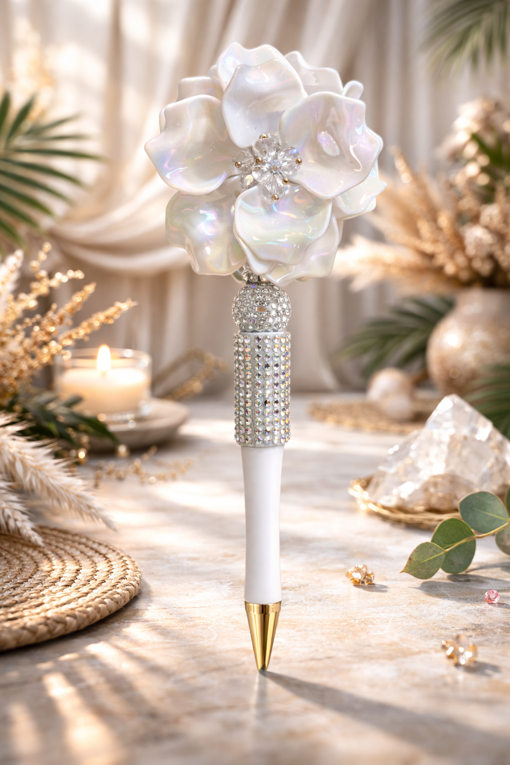White decorative bling pen with flower top on a table with decorative elements in the background. 