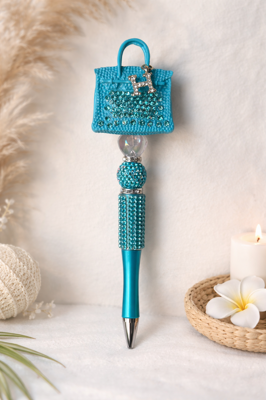 Blue decorative pen with a small H-handbag on top, on a soft background