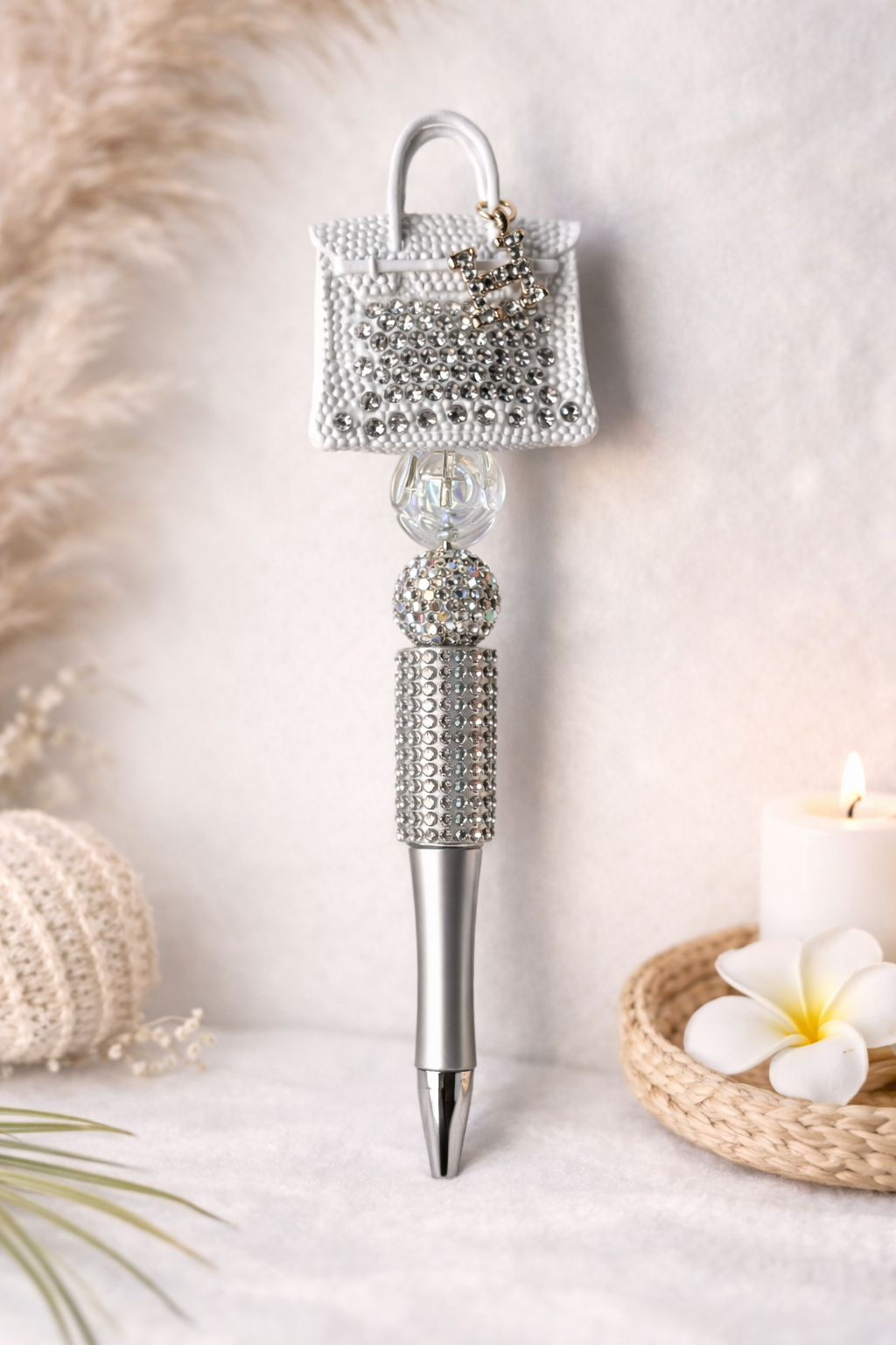 White decorative pen with a small H-handbag on top, on a soft background