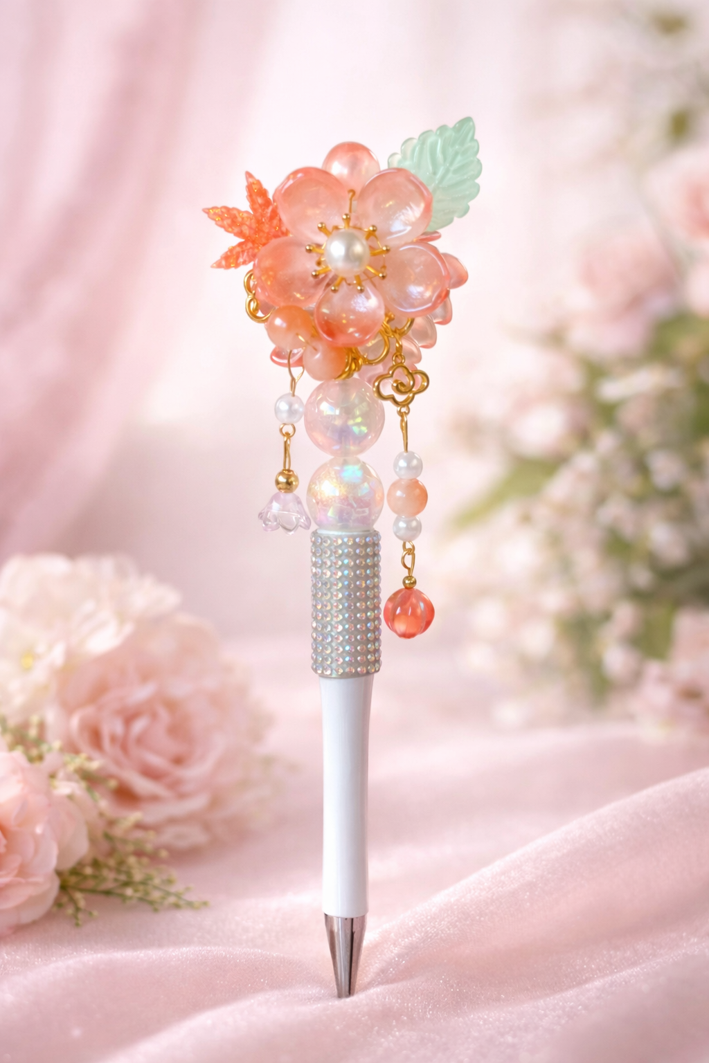 Orange flower and pearl beaded white decorative bling pen on a soft pink background