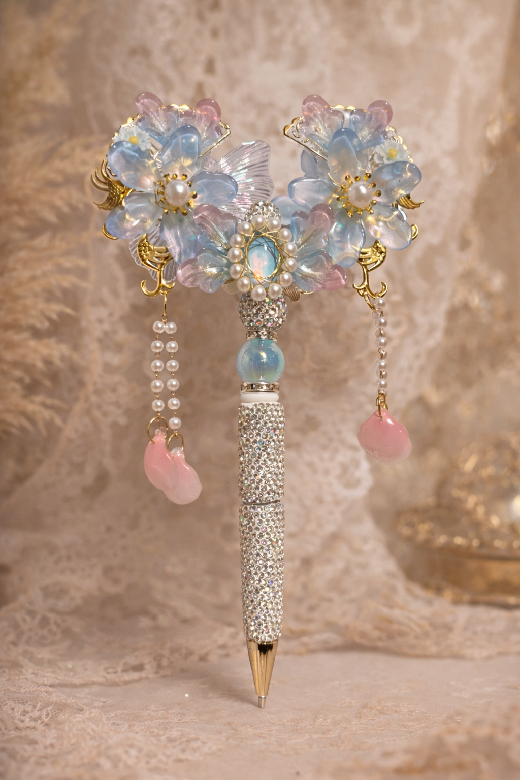 Extravagant decorative double-sided iridescent blue bling pen with large and small flowers & petals, gold accents, and pearl chain embellishments on a lace-textured background