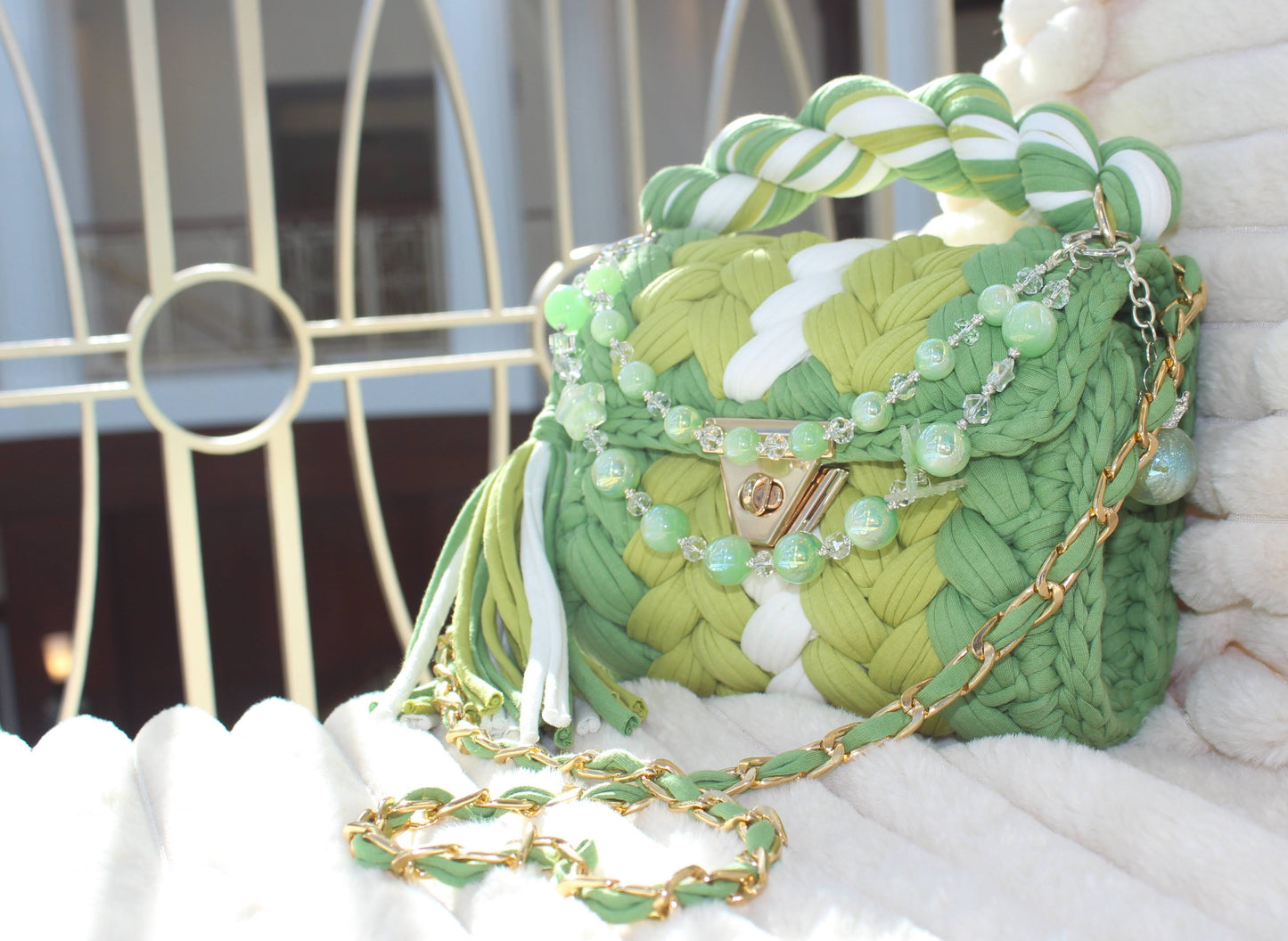 Side/Front view of the bag in natural lighting: Shades of Green & White Crochet woven texture with decorative keychain, sitting on a textured surface.