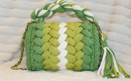 Back view of the bag: Shades of Green and White Crochet woven handbag with tassel, sitting on a White textured surface