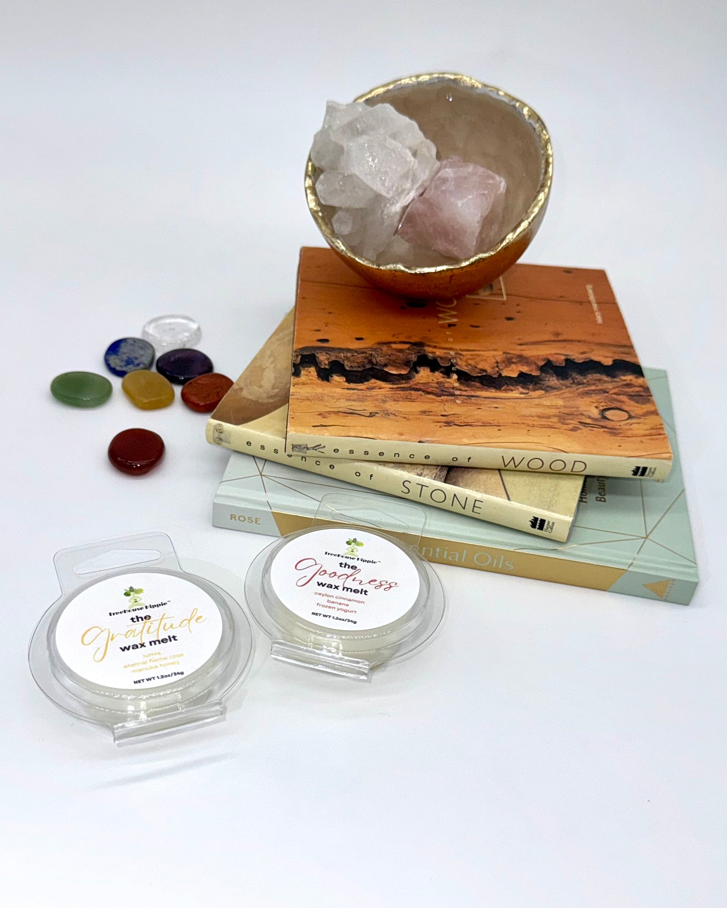 Two wax melts on a white surface with books, a crystal bowl, and stones in the background.