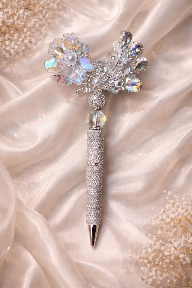 Decorative double-sided iridescent and silver bling pen with a large flower, crystal feather accents, and shiny embellishments on a silk background. 