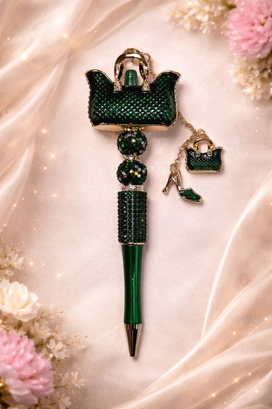 Green bling pen with purse charm decorative top on a soft fabric background with flowers