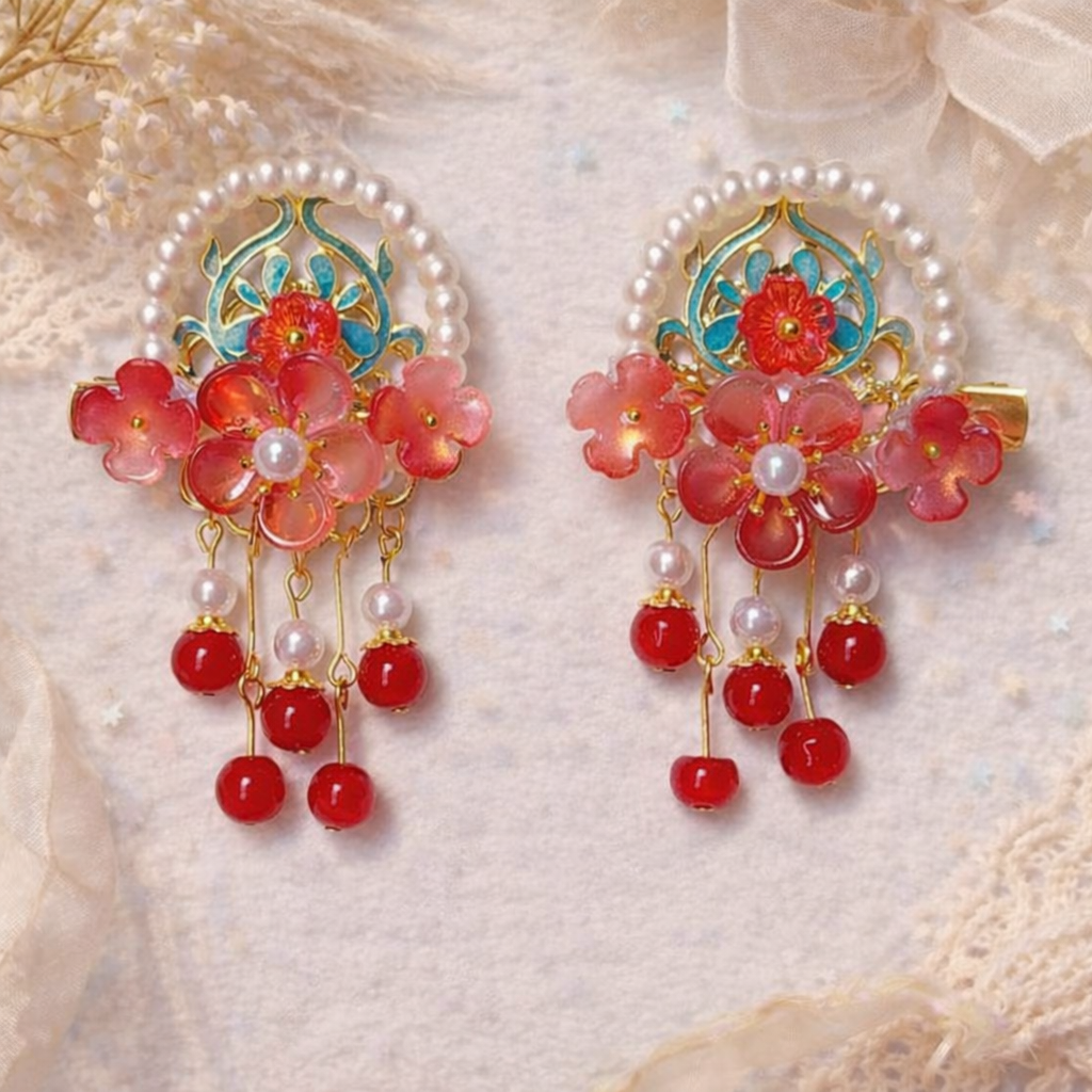 Ruby red flower hair clips with pearl bead bow and green details on a lace and paper textured white background