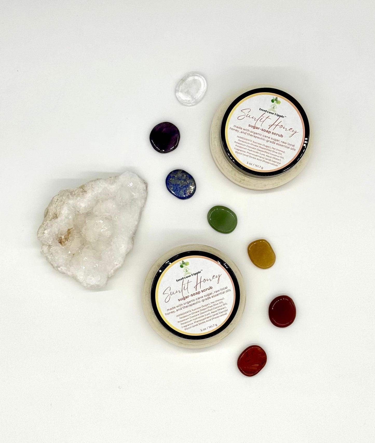 Two of TreeHouse Hippie's ‘Sunlit Honey’ scrubs sitting on a white background with chakra stones and a white quartz crystal. 