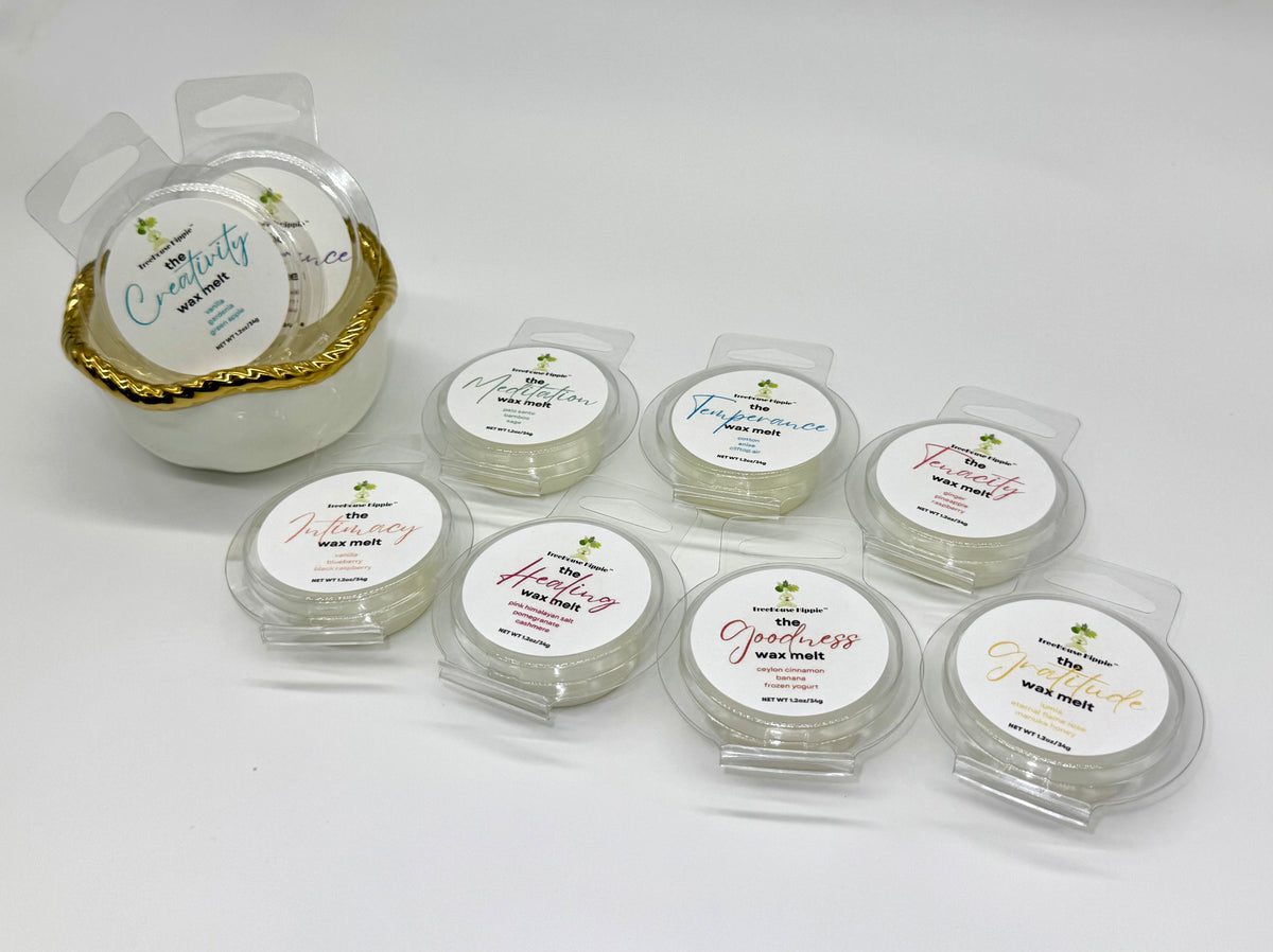 Collection of 10 wax melts in clear containers with white labels on a white background; white bowl with gold trim on the left side. 